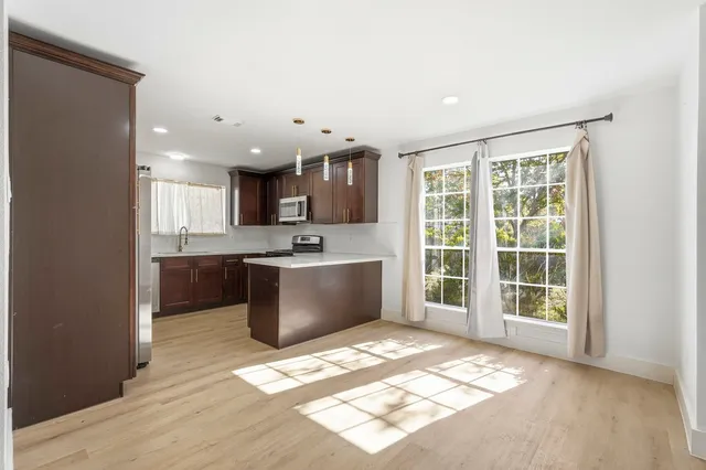 a view of kitchen with kitchen island a sink wooden floor and a large window