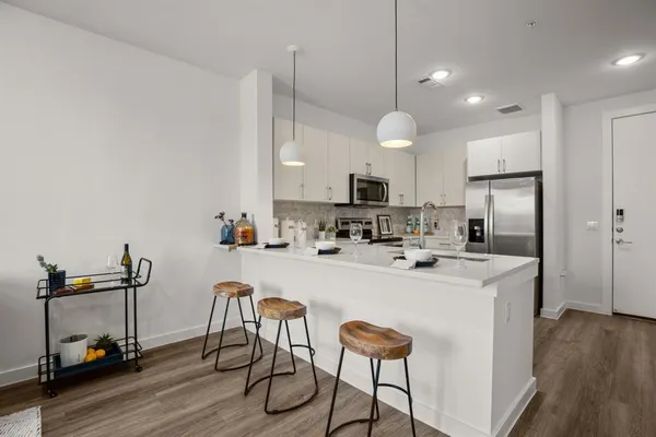 a kitchen with kitchen island a stove a chandelier a sink and a refrigerator