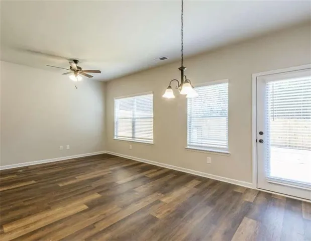 an empty room with wooden floor chandelier and windows