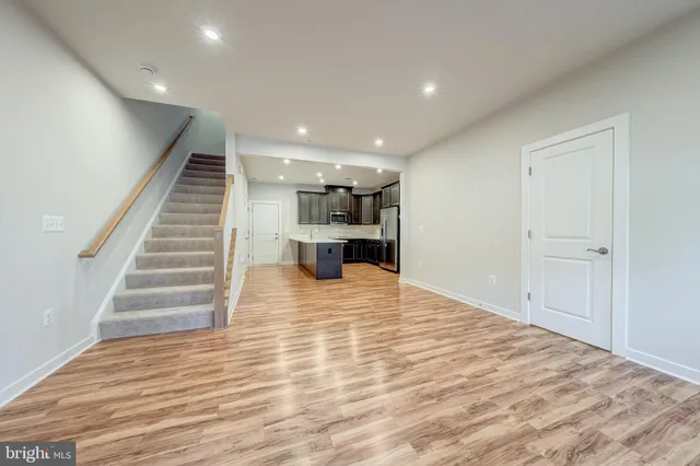 a view of kitchen and empty room with wooden floor