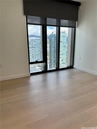 a view of an empty room with wooden floor and a window