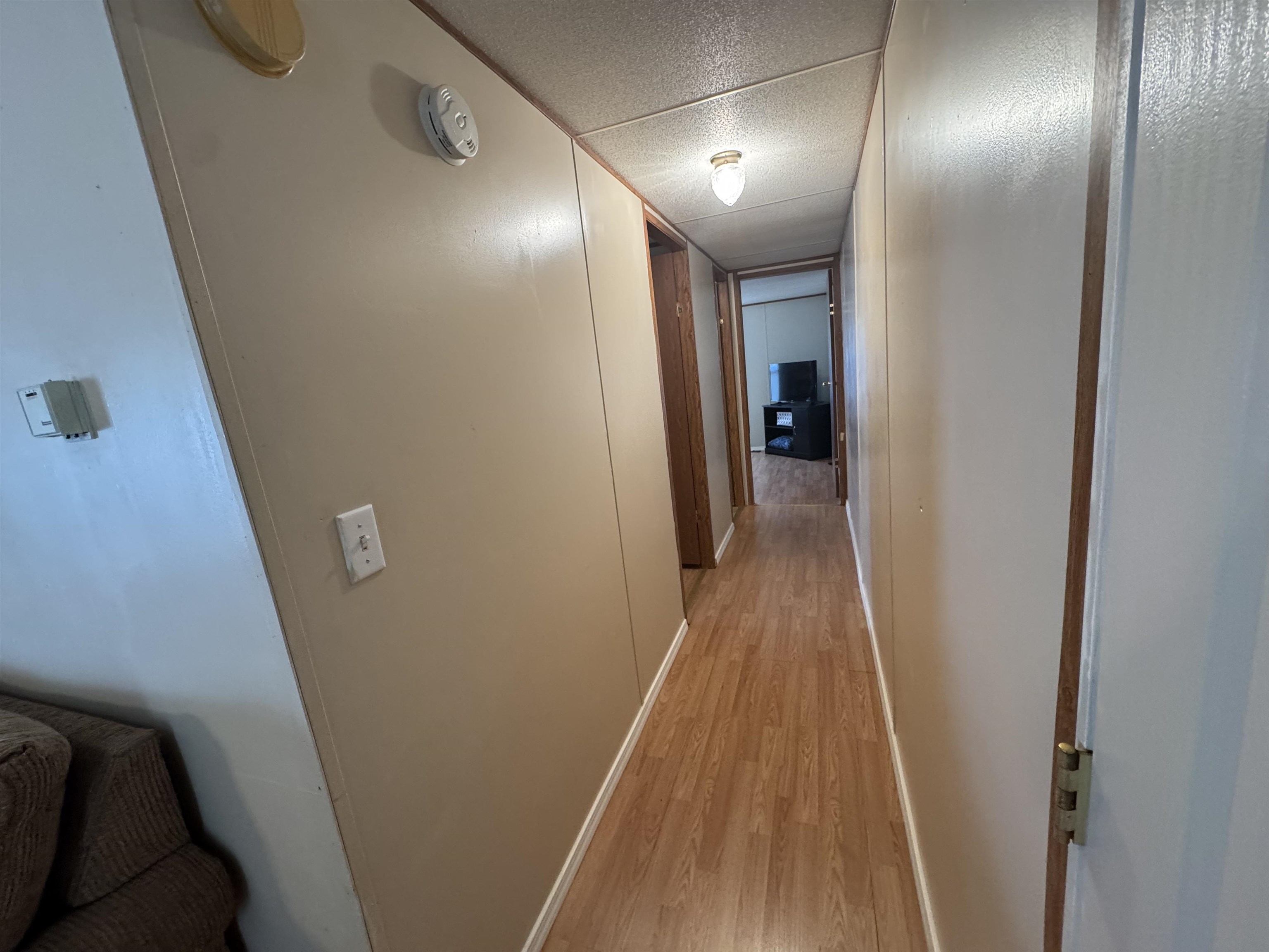 2511 Watkins Road Michie, TN 38357 - Photo 23 of 40 Interior hallway featuring wood-finish flooring, light-toned wall paneling, and an overhead flush-mount light fixture