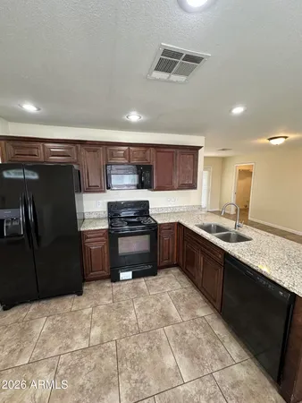 a large kitchen with granite countertop a stove a sink dishwasher a refrigerator and a microwave