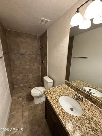 a bathroom with a granite countertop sink a toilet and a mirror