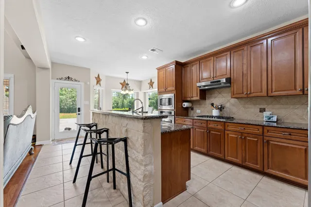a kitchen with stainless steel appliances granite countertop table chairs sink and cabinets