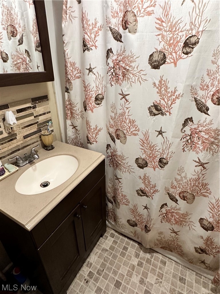 7145 Avon Belden Road North Ridgeville, OH 44039 - Photo 11 of 13 Bathroom featuring backsplash, vanity with extensive cabinet space, mirror, and light tile floors