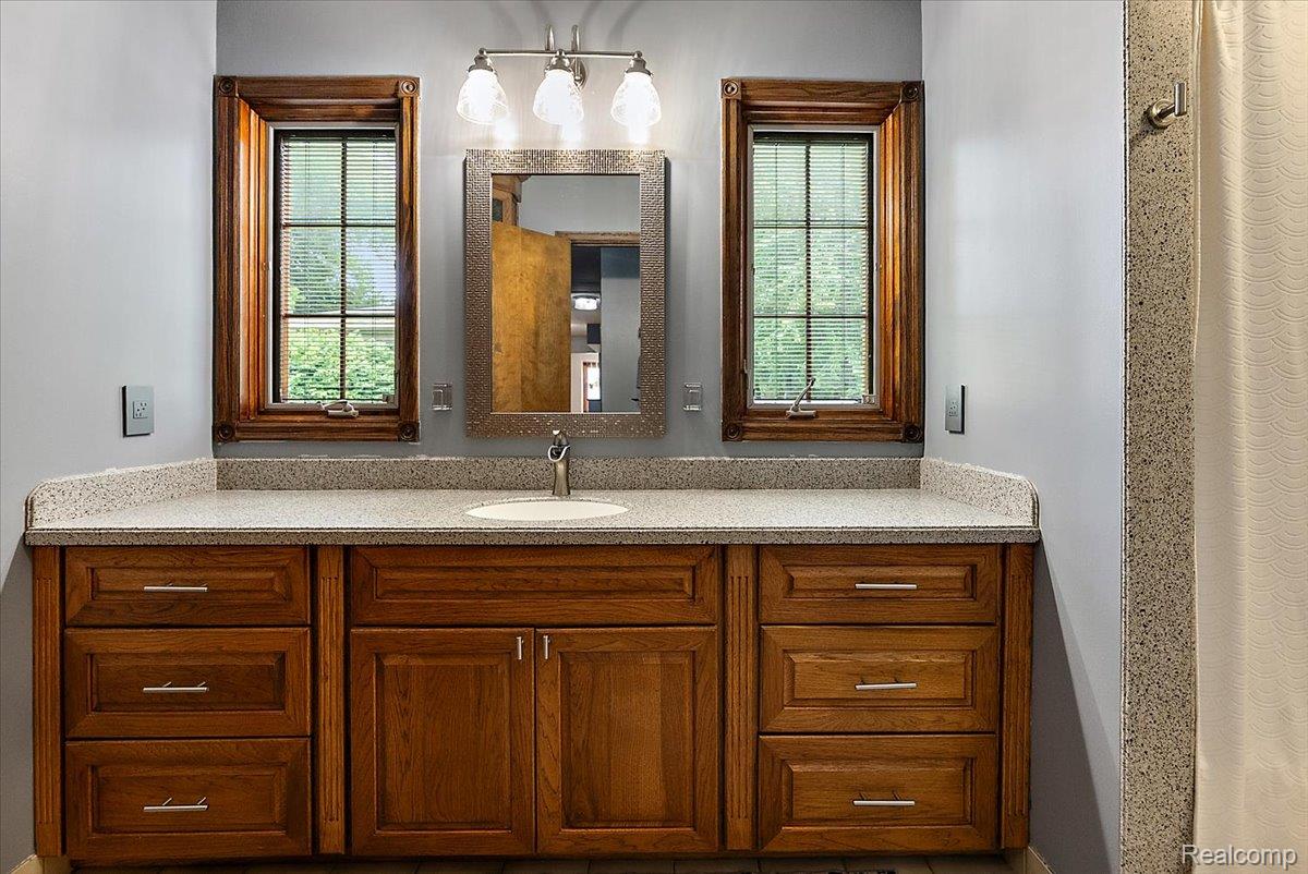 60718 Campground Road Washington, MI 48094 - Photo 26 of 37 Bathroom vanity with an integrated sink, wood-finish cabinetry, and a light-toned countertop