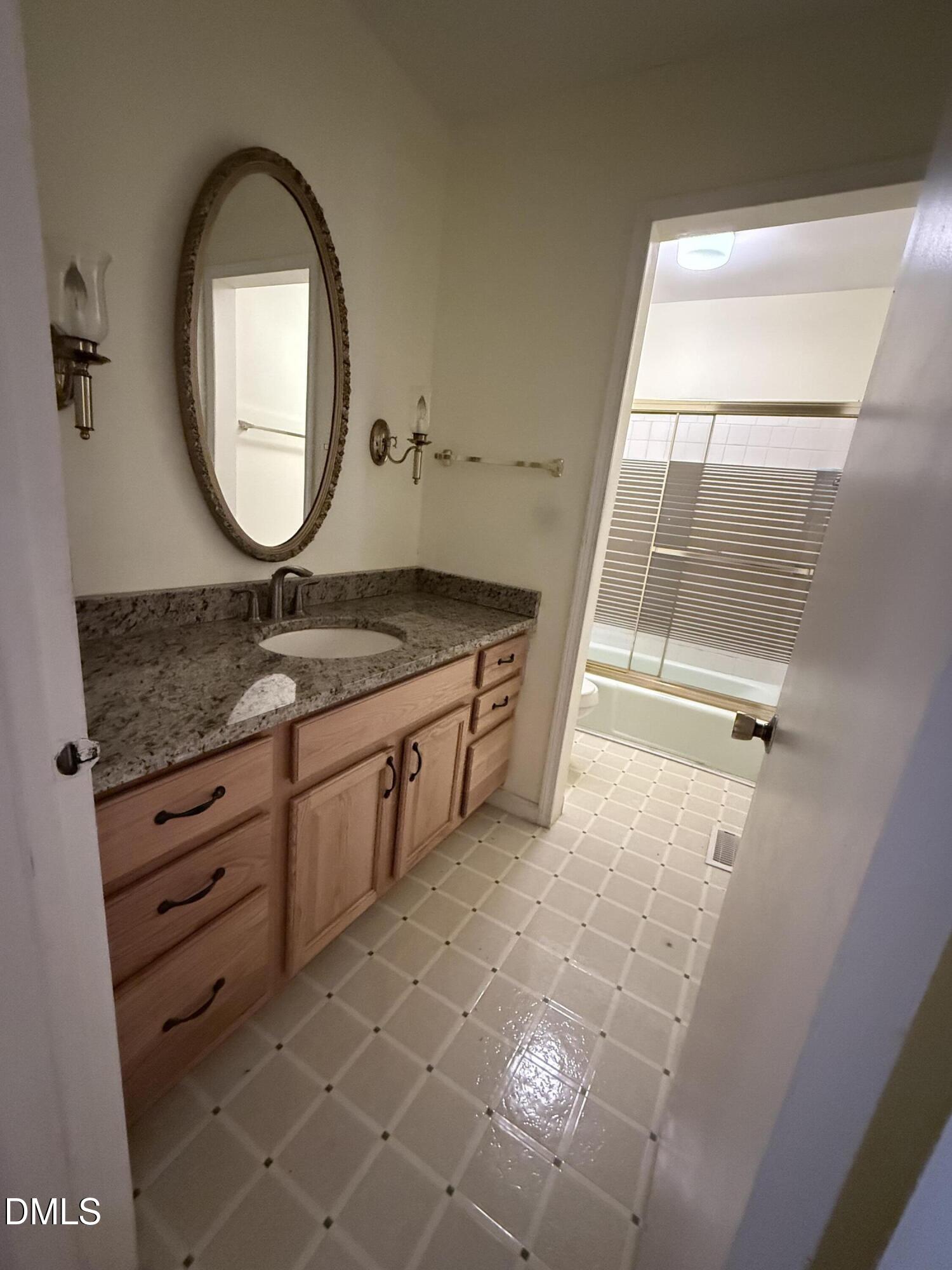 1010 Wyldewood Road Durham, NC 27704 - Photo 16 of 26 a bathroom with a granite countertop sink a mirror and a vanity