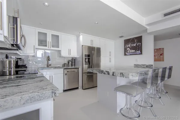 a kitchen with stainless steel appliances granite countertop a stove top oven a sink a refrigerator and white cabinets