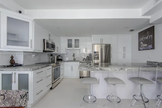 a kitchen with stainless steel appliances granite countertop a sink a stove a refrigerator cabinets and chairs