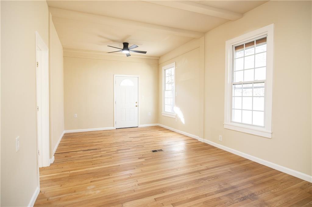 163 Rabbit Town Road Tate, GA 30177 - Photo 10 of 32 an empty room with wooden floor ceiling fan and windows