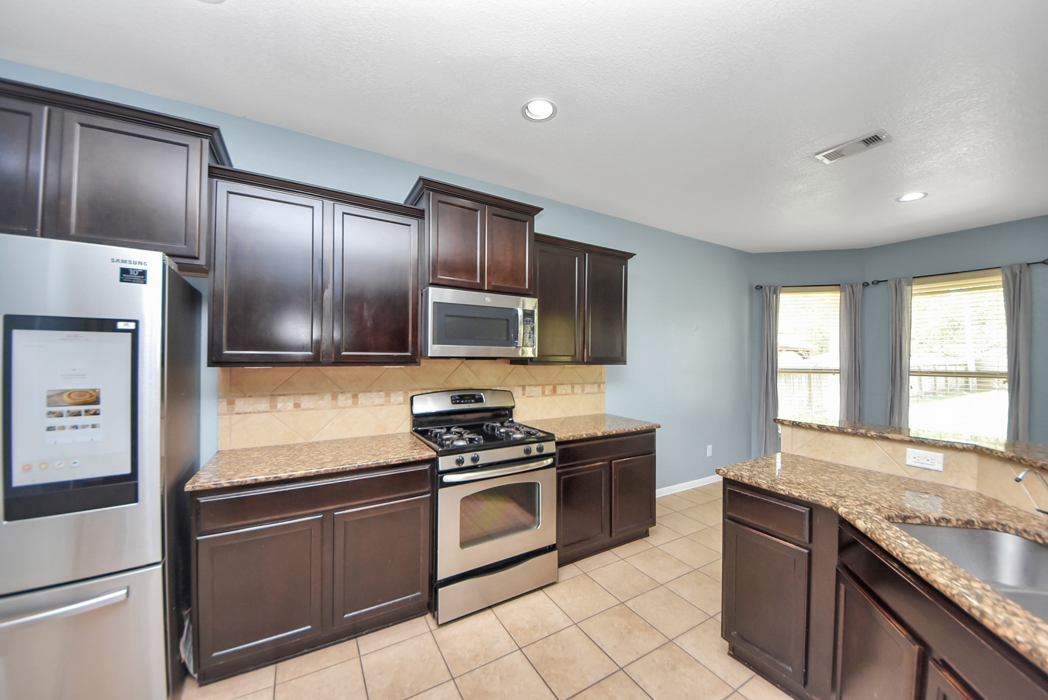 33227 Greenfield Forest Drive Spring, TX 77382 - Photo 17 of 50 a kitchen with granite countertop stainless steel appliances cabinets a sink and a window