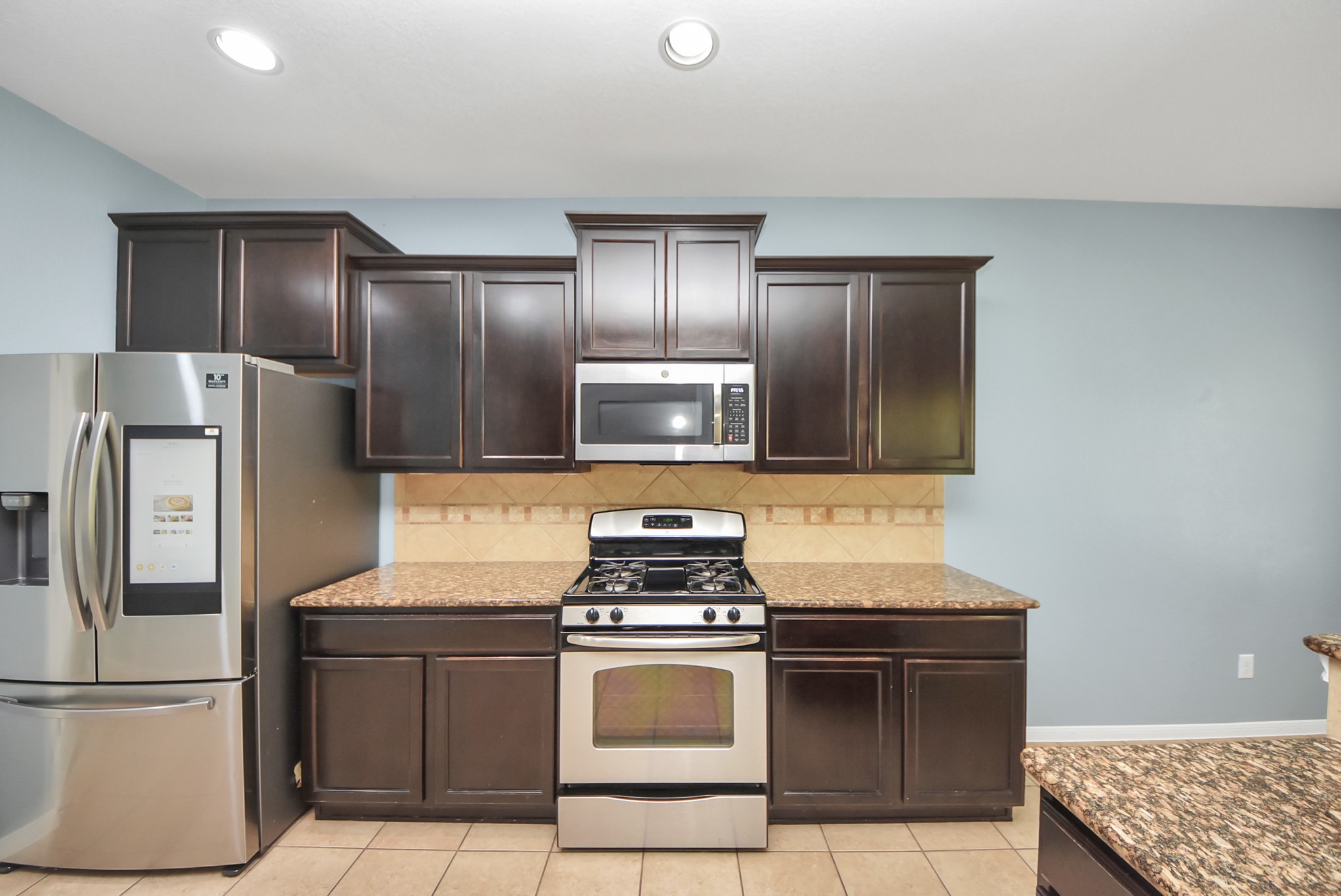 33227 Greenfield Forest Drive Spring, TX 77382 - Photo 40 of 50 a kitchen with a stove refrigerator and microwave