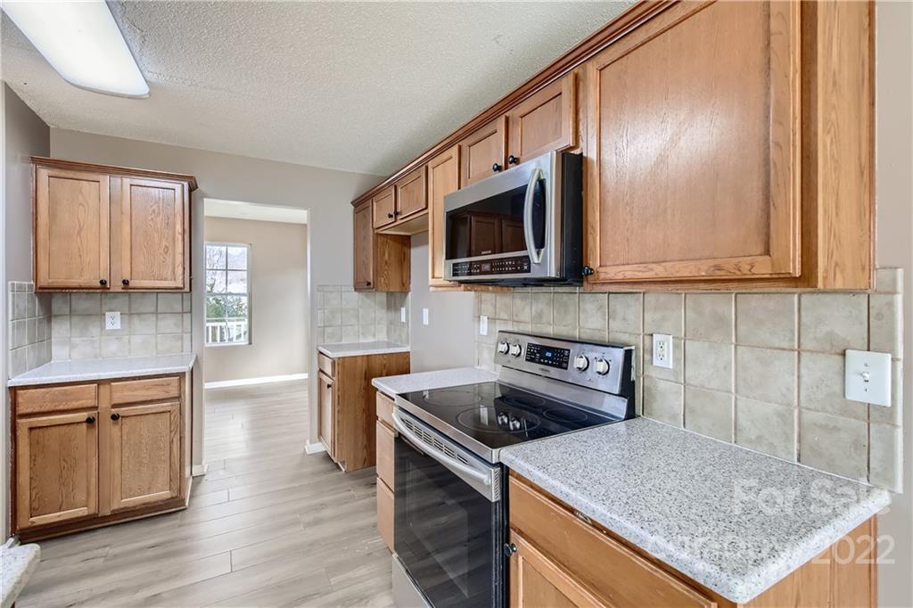 7005 Copper Ridge Court Gastonia, NC 28056 - Photo 13 of 33 a kitchen with stainless steel appliances granite countertop a sink stove microwave and cabinets