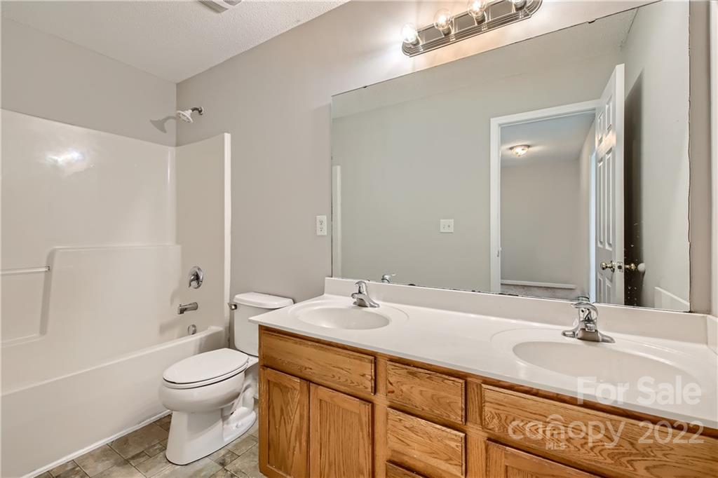 7005 Copper Ridge Court Gastonia, NC 28056 - Photo 26 of 33 a bathroom with a granite countertop sink a toilet and shower