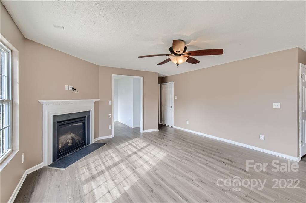 7005 Copper Ridge Court Gastonia, NC 28056 - Photo 3 of 33 a view of a livingroom with a fireplace a chandelier fan and wooden floor