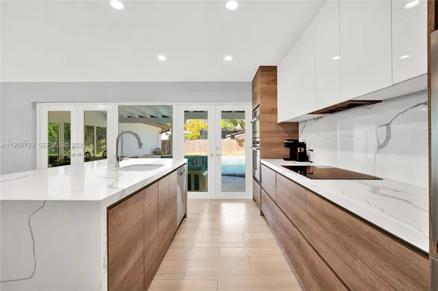 a large kitchen with stainless steel appliances a large counter top a stove and a sink