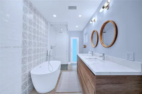 a spacious bathroom with a bathtub a double vanity sink and a mirror
