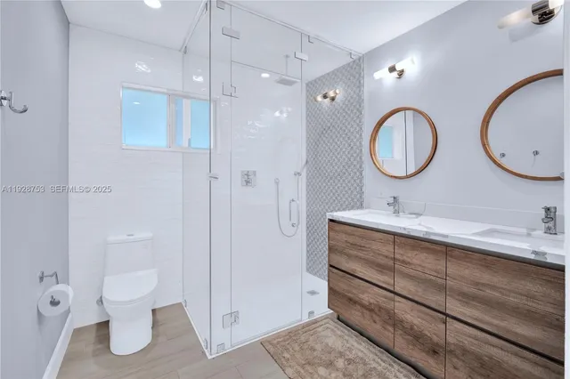 a bathroom with a double vanity sink toilet and shower