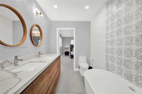 a en suite bathroom with a granite countertop double vanity sink and a mirror