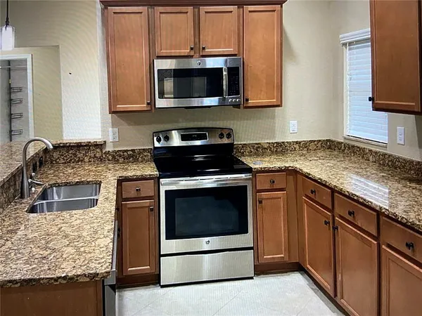 a kitchen with granite countertop a sink stove and microwave