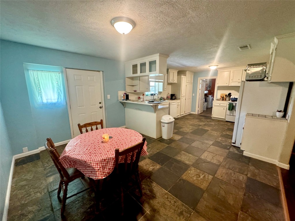 303 Charles Street Cleveland, TX 77327 - Photo 18 of 43 a kitchen with a dining table chairs and a refrigerator