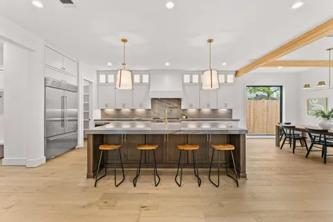 a kitchen with kitchen island granite countertop a table chairs sink and cabinets