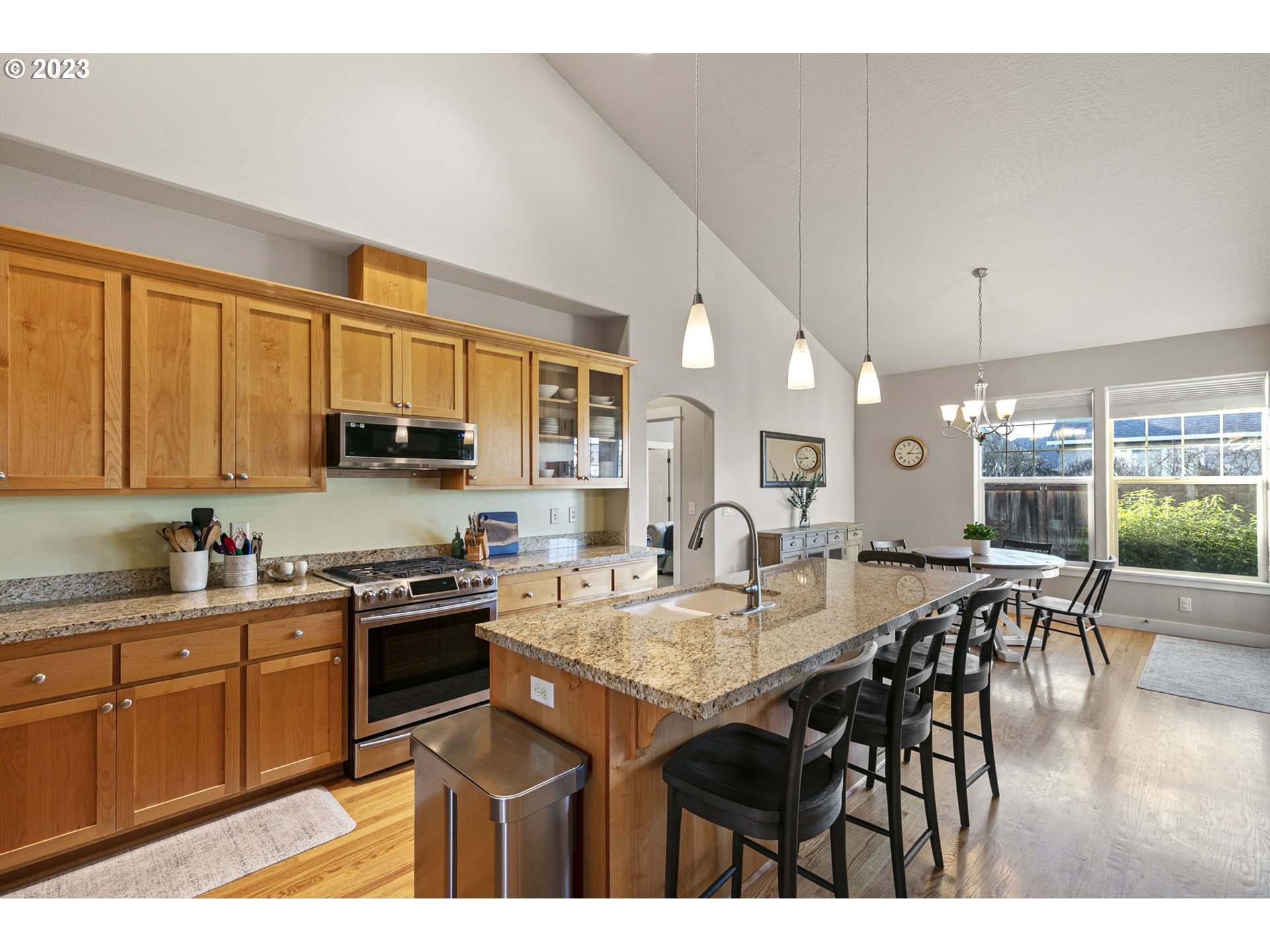1200 South 41st Place Springfield, OR 97478 - Photo 12 of 34 a open kitchen with stainless steel appliances granite countertop a stove top oven a sink a dining table and chairs with wooden floor