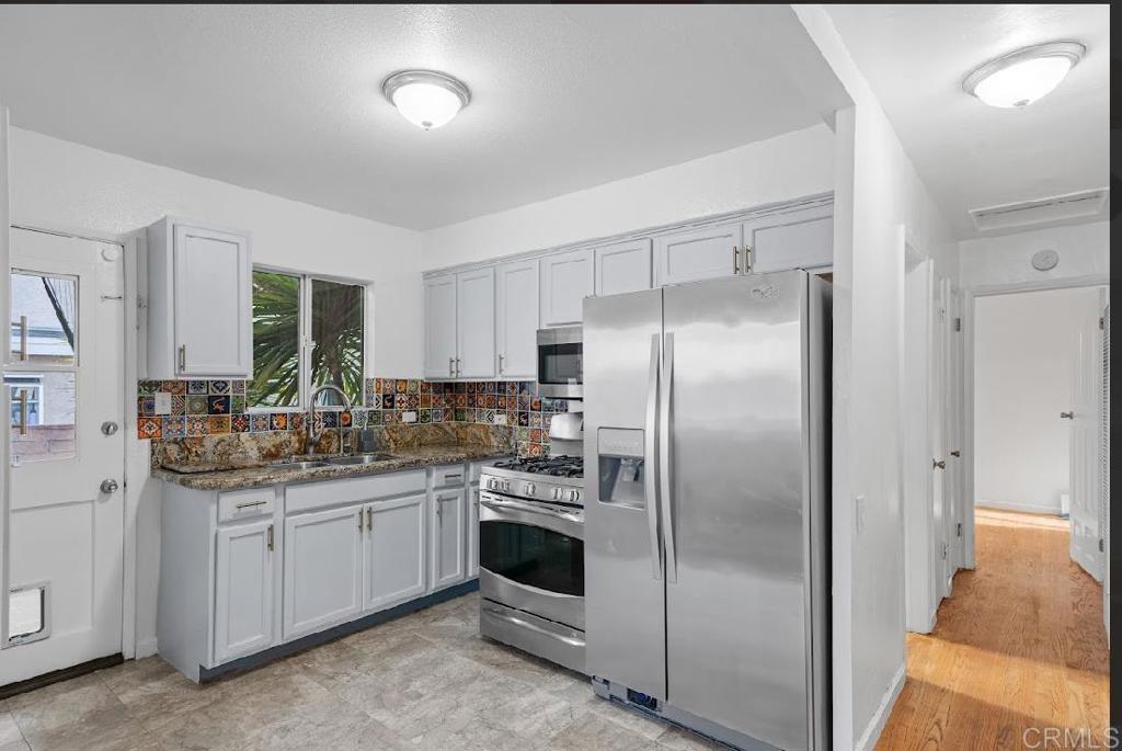 3964 Delta Street San Diego, CA 92113 - Photo 5 of 39 a kitchen with stainless steel appliances a refrigerator sink and cabinets