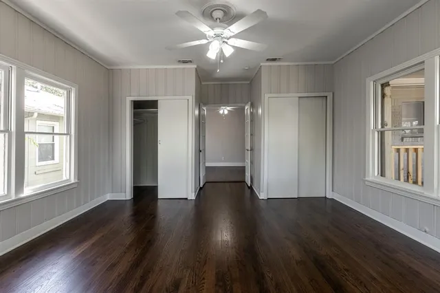 a view of empty room with wooden floor and fan