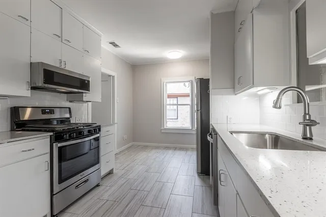 a kitchen with stainless steel appliances granite countertop a sink a stove and a microwave