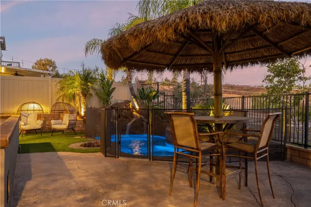 a view of a patio with table and chairs under an umbrella with a small yard