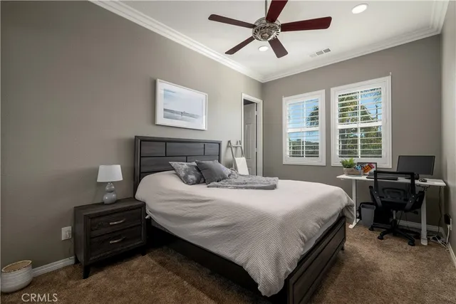 a bedroom with a bed a desk and chair with window