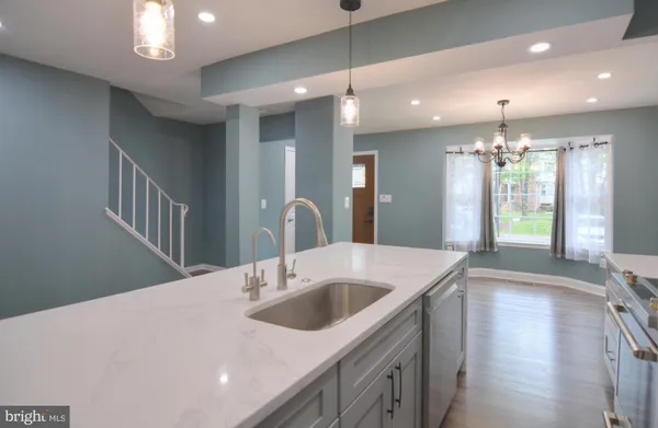 a kitchen with a sink chandelier and wooden floor