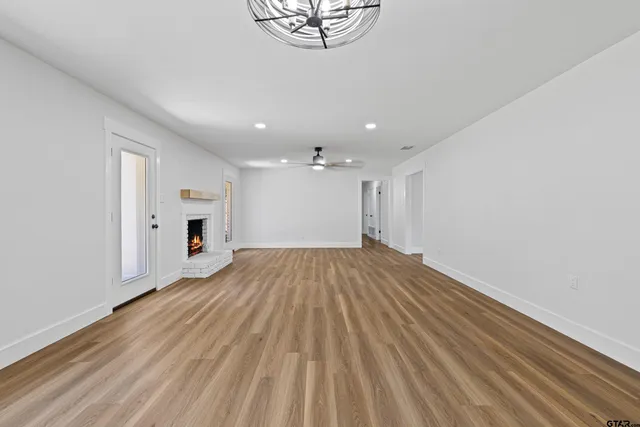 a view of an empty room with a window and wooden floor