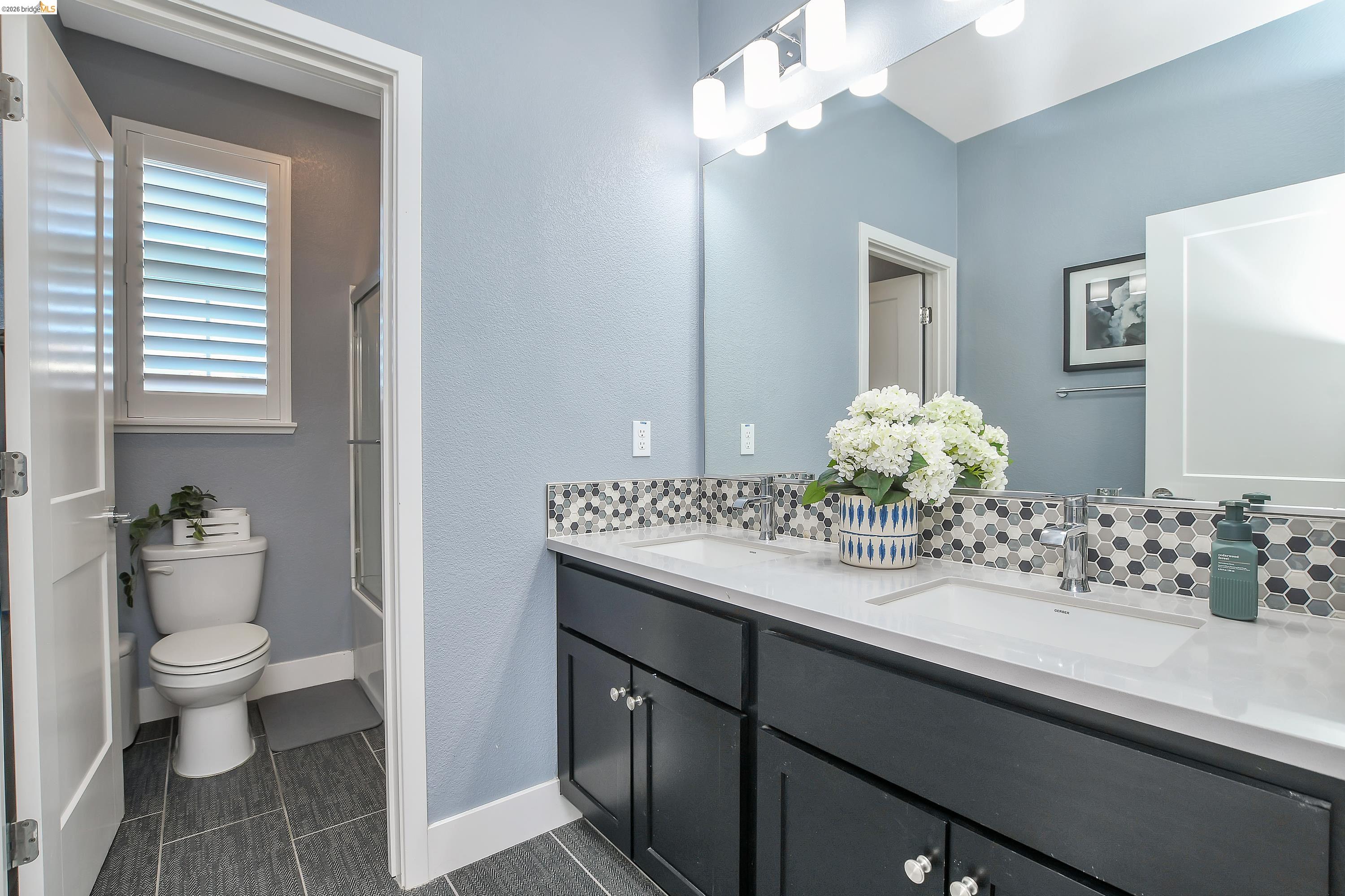 829 Hardcastle Ranch Road Oakley, CA 94561 - Photo 22 of 41 Dual sink vanity with white countertop and black cabinetry, complemented by a hexagonal tile backsplash and overhead vanity lighting