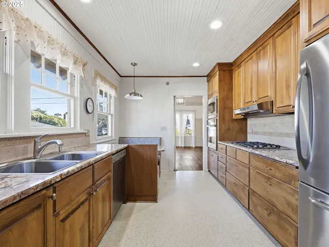 a kitchen with stainless steel appliances granite countertop a refrigerator a sink dishwasher stove and oven