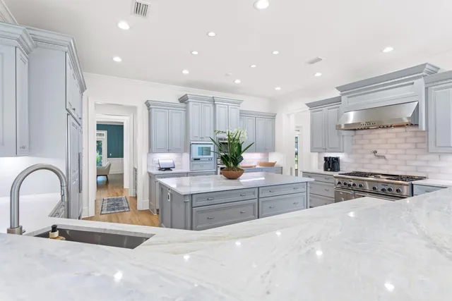 a large kitchen with stainless steel appliances a large counter top a stove and a refrigerator