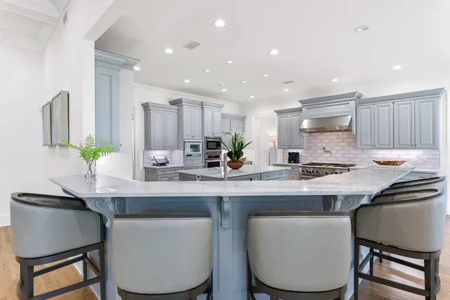 a kitchen with kitchen island granite countertop a dining table chairs cabinets and stainless steel appliances