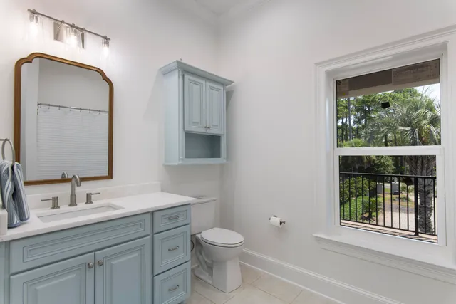 a bathroom with a toilet a sink a mirror and next to a window