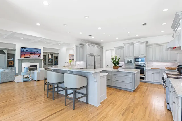 a kitchen with stainless steel appliances granite countertop a stove top oven a sink dishwasher and a dining table with wooden floor