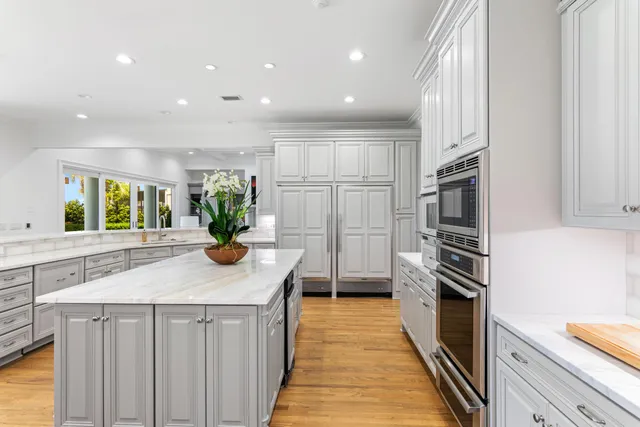 a kitchen with stainless steel appliances kitchen island granite countertop a refrigerator a stove and a sink with wooden floor