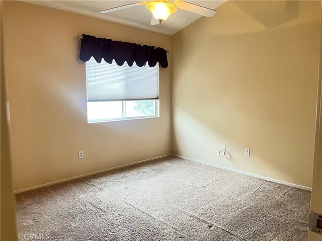 an empty room with a window and a chandelier fan