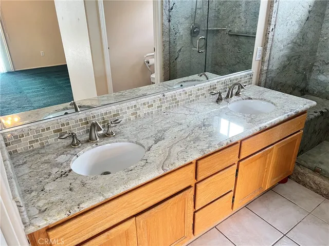 a bathroom with a granite countertop shower a sink and a mirror