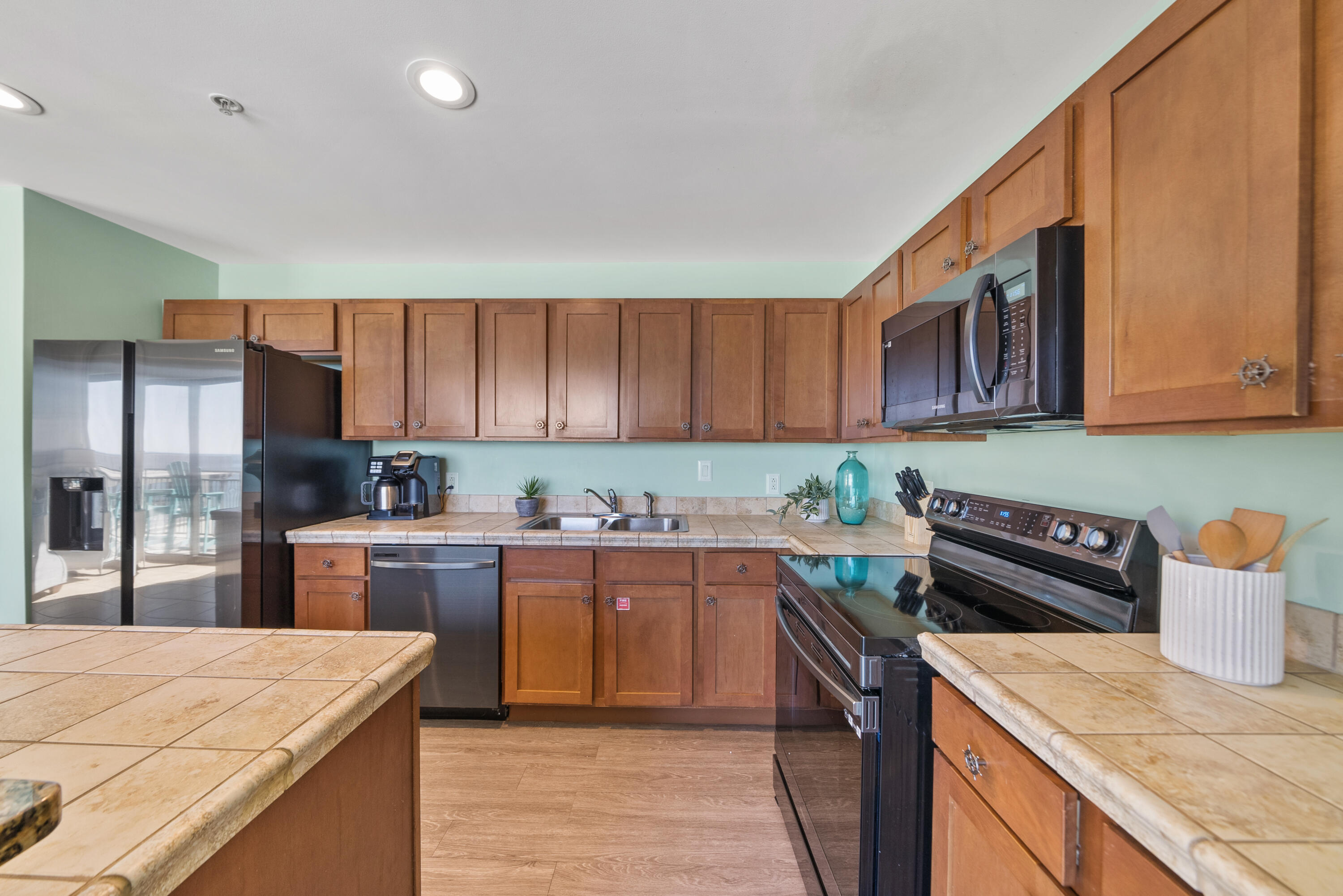 15100 Front Beach Road, Unit 1604 Panama City Beach, FL 32413 - Photo 15 of 66 a kitchen with stainless steel appliances granite countertop a stove top oven a sink dishwasher and wooden cabinets with wooden floor