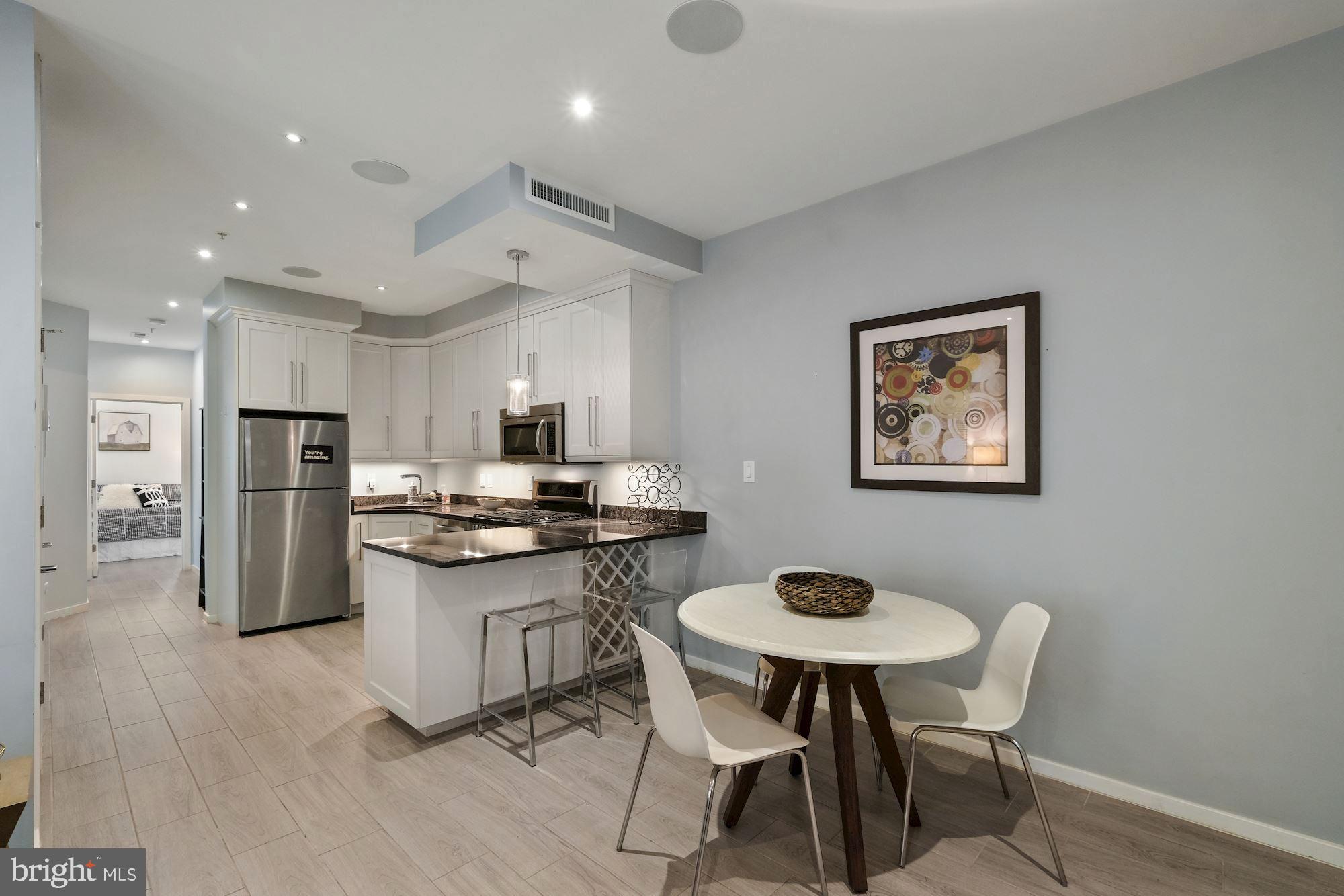 756 Park Road Northwest, Unit 2 Washington, DC 20010 - Photo 8 of 48 a kitchen with stainless steel appliances granite countertop a stove a refrigerator a kitchen island with a dining table and chairs