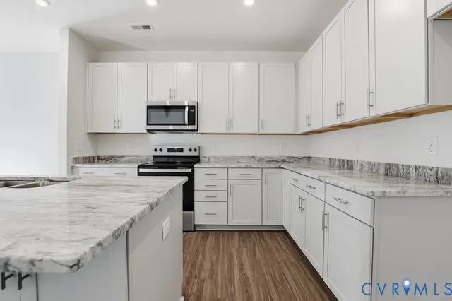 a kitchen with granite countertop white cabinets and stainless steel appliances