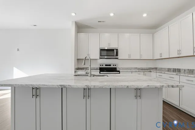 a kitchen with stainless steel appliances granite countertop a sink a stove and a refrigerator