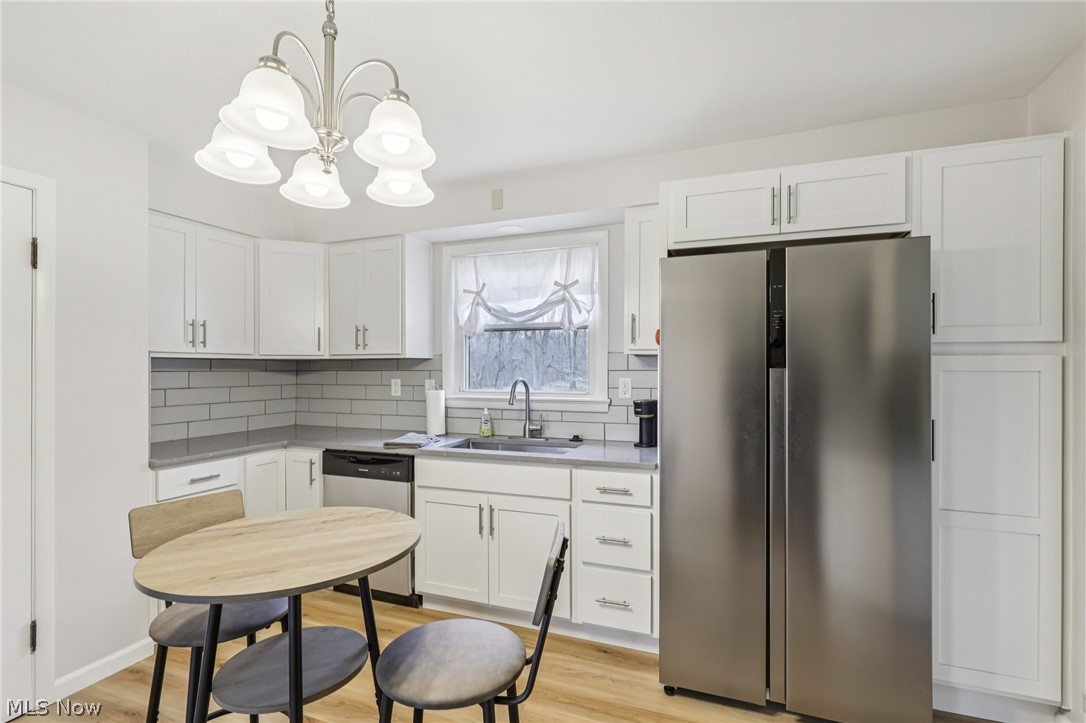 34825 Aurora Road Solon, OH 44139 - Photo 7 of 13 Kitchen featuring stainless steel appliances, light wood-style floors, white cabinets, and hanging lights