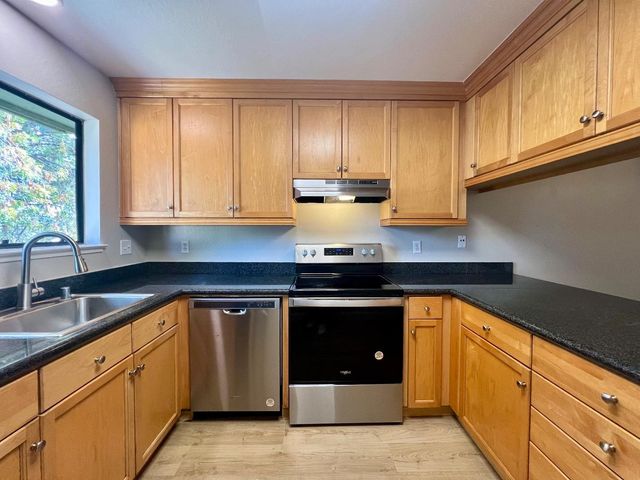 a kitchen with granite countertop cabinets stainless steel appliances and a sink